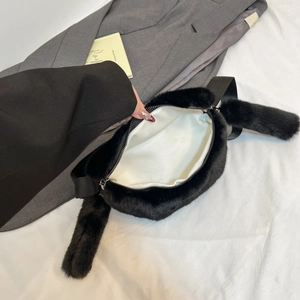 Detail of black faux fur waist bag with durable white twill lining and metal zipper