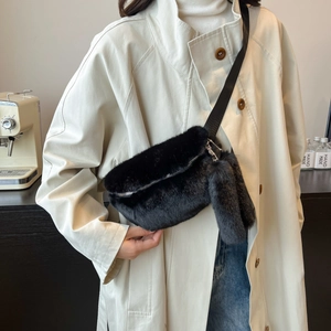 Close-up of black faux fur waist bag with plush bunny keychain and adjustable strap