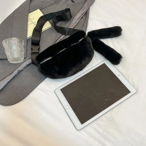 Detailed view of black plush waist bag featuring fuzzy rabbit ears and silver zipper