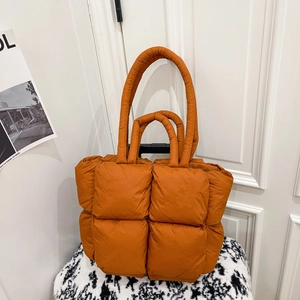 Burnt orange puffer tote bag with quilted nylon texture and versatile double handles