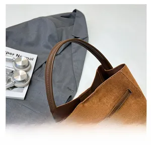 Détail du sac à main en daim marron avec fermoir rotatif en métal et poignée rétro