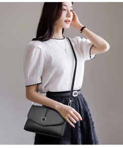 Détail d'un sac à main noir en cuir grainé avec boucle argentée et fine bandoulière
