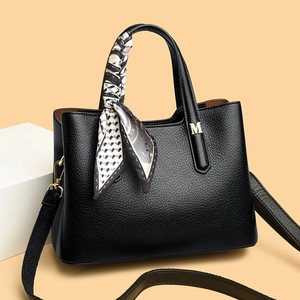 Borsa tote in pelle litchi nera con foulard e logo M dorato su sfondo beige caldo