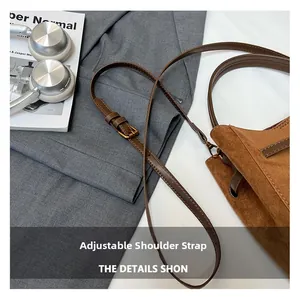 Détail de la bandoulière réglable sur le sac rétro en daim marron élégant