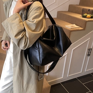 Minimalist black matte leather tote bag shown on shoulder for daily commute style