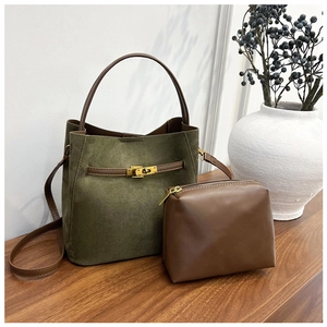 Détail du sac seau en daim vert avec fermoir doré et pochette en cuir marron assortie