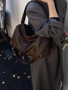 Detail of dark brown leather tote bag with wide strap styled with grey trench coat