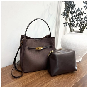 Gros plan sur le sac seau en cuir givré marron foncé avec fermoir rotatif et pochette assortie