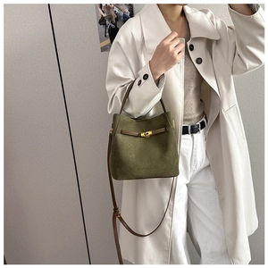 Détail du sac seau rétro en daim vert avec fermoir doré rotatif et poignée en cuir