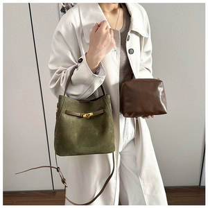 Détail du sac seau givré vert foncé avec anses en cuir marron et pochette assortie