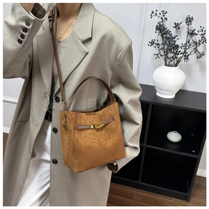 Détail du sac seau en daim marron mat avec boucle dorée et bandoulière amovible