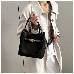 Détail du sac seau noir mat avec fermoir doré porté par un mannequin avec bandoulière