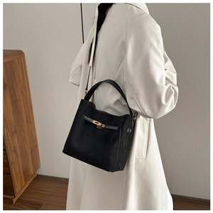 Détail du sac seau noir en daim avec fermoir doré et bandoulière pour femmes