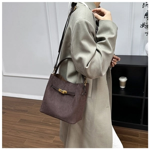 Détail du sac seau en daim marron givré avec fermoir pivotant doré et poignée solide