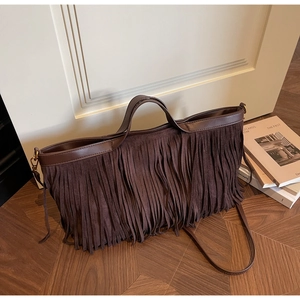 Détail d'un sac à franges en daim marron foncé avec bordures en cuir et style bohème