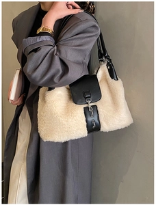 Close-up of beige plush and black PU leather patchwork shoulder bag with metal buckle detail