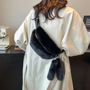 Chic black faux fur crossbody bag with plush pom-poms worn by model in a cafe