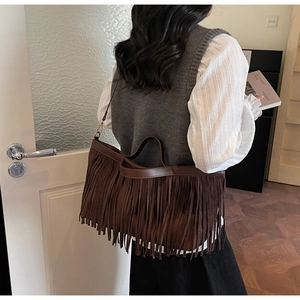 Détail du sac en daim marron foncé avec de longues franges bohèmes et une bandoulière rétro
