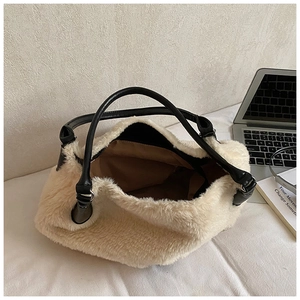 Detail of plush cream faux fur tote bag with black leather handles on a desk