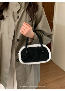 Detail der flauschigen Bowling-Tasche in Schwarz-Weiß, gehalten von einem Model im Mantel
