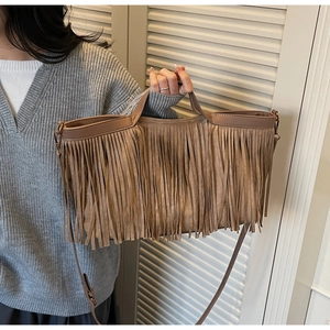 Détail d'un sac bandoulière en daim avec de longues franges bohèmes et boucles dorées