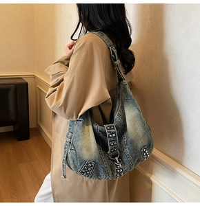 Détail d'un grand sac hobo en jean avec clous argentés et large bandoulière