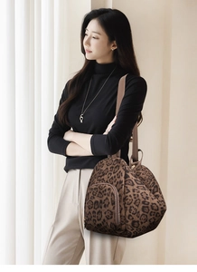 Detailed shot of leopard print shoulder bag featuring a wide strap and front zipper pocket