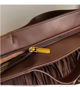 Gros plan détaillé sur la fermeture éclair dorée et la doublure rayée d'un sac à franges