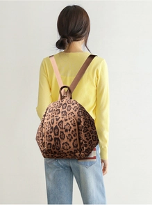 Detail view of large leopard print backpack with durable nylon straps on a model