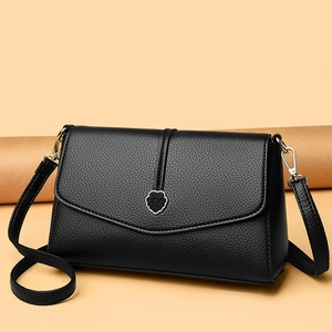 Sac à bandoulière en cuir noir avec boucle cœur sur un fond orange chaleureux