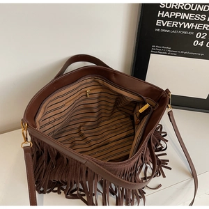 Détails intérieurs du sac bandoulière en daim avec doublure rayée et poche zippée