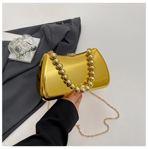 Close-up of gold mirror finish evening bag with beaded handle and chain strap