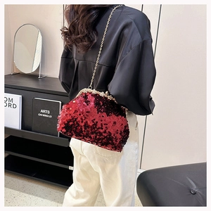Detail of red sequin evening bag with gold chain strap and rhinestone clasp on a model