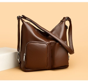 Detail of dark brown lychee texture leather shoulder bag with silver metal zippers