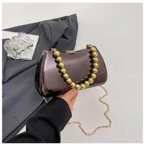Detail of mirror-finish evening bag with gold bead handle and metallic chrome shell