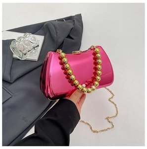 Detail of hot pink metallic clutch bag featuring chunky gold bead handle and chain