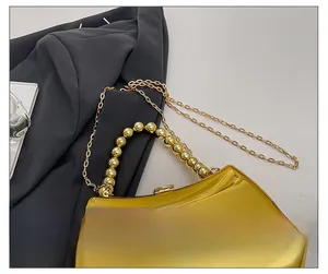 Detail of elegant gold mirror evening bag with acrylic beaded handle and chain strap