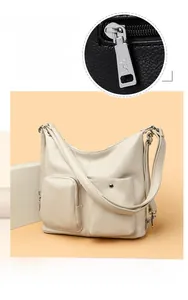 Detail of cream pebbled leather handbag featuring dual front pockets and silver hardware