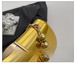Close-up of polished gold metal evening bag with glossy hardware and bead chain link