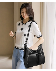Detail shot of black hobo bag with pebble leather texture and functional front pockets