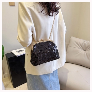 Detail of black sequined evening clutch with diamond flower clasp and gold chain strap