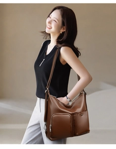 Close-up of brown textured leather hobo bag with adjustable strap and functional zippers