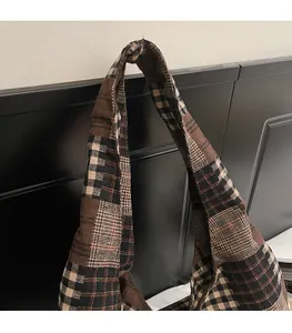 Detail of the wide integrated shoulder strap on a brown checkered crossbody bag