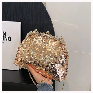 Detailed shot of gold sequins evening bag with a rhinestone floral metal clasp and chain