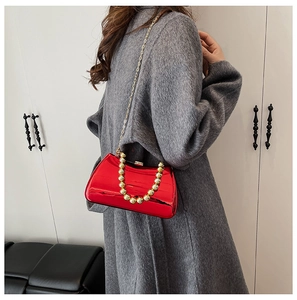 Detail of red metallic hard shell evening clutch with gold bead handle and chain strap