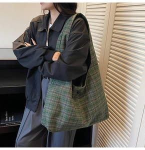 Green plaid tote bag made of thick wool fabric worn by model in casual indoor setting