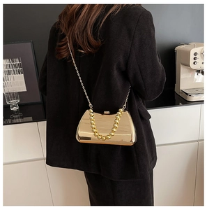 Close-up of a gold evening clutch with a spherical handle and chain strap on a black blazer