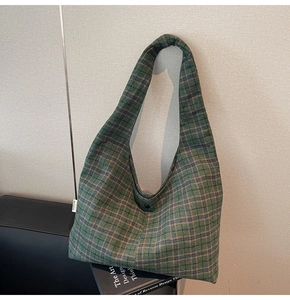 Detail of checkered canvas tote bag with resin button closure and green plaid texture