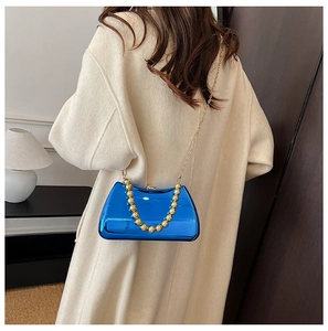Detail of bright blue metallic clutch with gold bead handle and chain strap