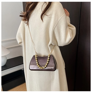 Chic gunmetal mirror evening bag with gold bead handle shown on shoulder of a model